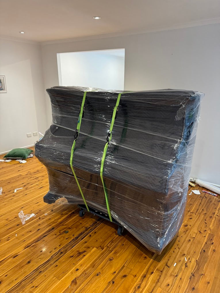 Upright piano professionally wrapped and secured with straps for safe transport — AllCare Removalists Perth piano moving specialists.