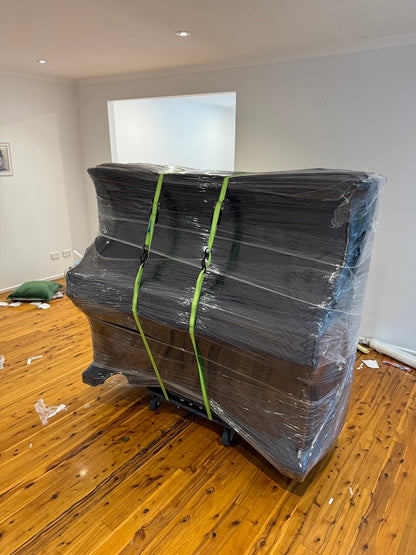 Upright piano professionally wrapped and secured with straps for safe transport — AllCare Removalists Perth piano moving specialists.