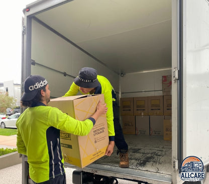 Two professional removalists in Perth loading labeled boxes into an AllCare moving truck, demonstrating safe and efficient residential moving services.